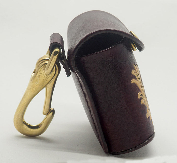 Mahogany leather dog waste bag dispenser with solid brass hardware,, photographed from the side to display the contrast stitching and brass clip.
