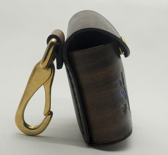 Grey leather dog waste bag dispenser with solid brass hardware and black contrast stitching.