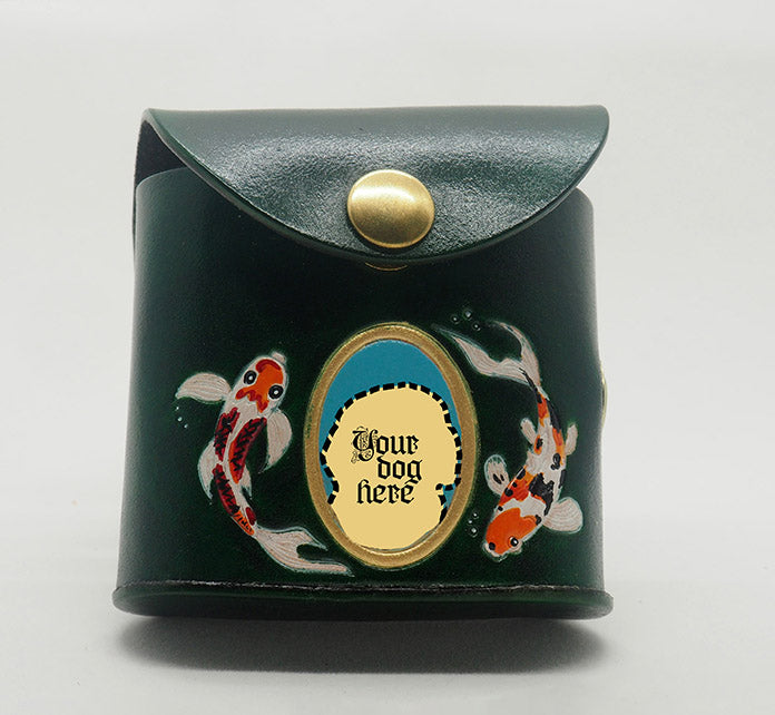 Green leather dog waste bag dispenser with brass snap hardware. Design features a gold painted frame with an aqua colored background  and the text "Your dog here".  Hand-painted koi fish wreath the frame.