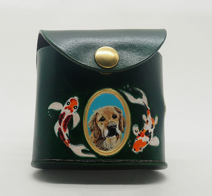 Green leather dog waste bag dispenser with brass snap hardware. Design features a portrait of a golden retriever dog against an aqua colored background with a gold painted frame, with hand-painted koi fish wreathing the frame.