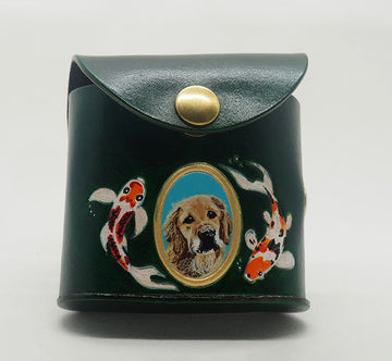 Green leather dog waste bag dispenser with brass snap hardware. Design features a portrait of a golden retriever dog against an aqua colored background with a gold painted frame, with hand-painted koi fish wreathing the frame.