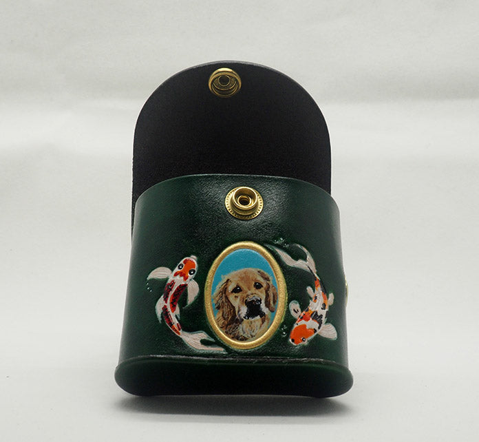 Green leather dog waste bag dispenser with brass snap hardware, opened to show the brown interior. Design features a portrait of a golden retriever dog against an aqua colored background with a gold painted frame, with hand-painted koi fish wreathing the frame.