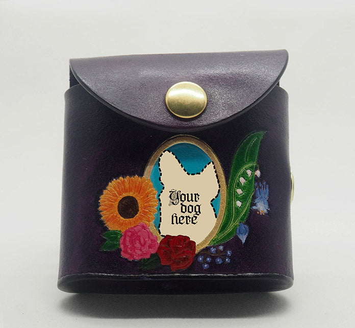 Eggplant purple leather dog waste bag dispenser with brass snap hardware. Design features a gold-painted portrait frame with a bright blue colored background and the text "Your dog here," wreathed with an arrangement of flowers.