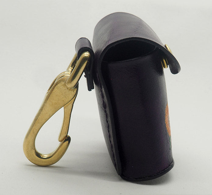 Eggplant purple leather dog waste bag dispenser with solid brass hardware, shown from the side to display the halter-style clip and matching stitching.